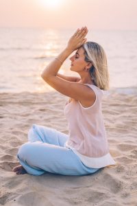 a woman meditating at the beach